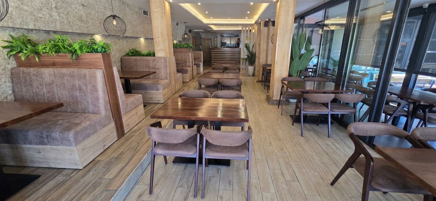 Sala restorana: separei sa zelenilom, drveni stolovi i šank u dnu
